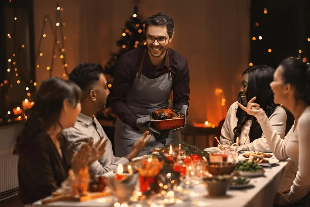 A group of people enjoying a festive dinner with a variety of dishes, including a roasted turkey, at a warmly lit table decorated with candles and holiday lights. This scene is part of Global End-of-Year Desserts.