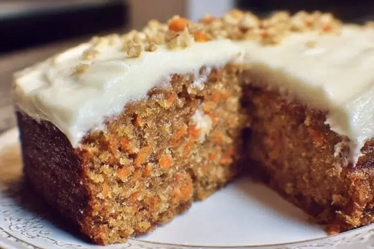 A slice of dairy-free carrot cake garnished with walnuts and icing
